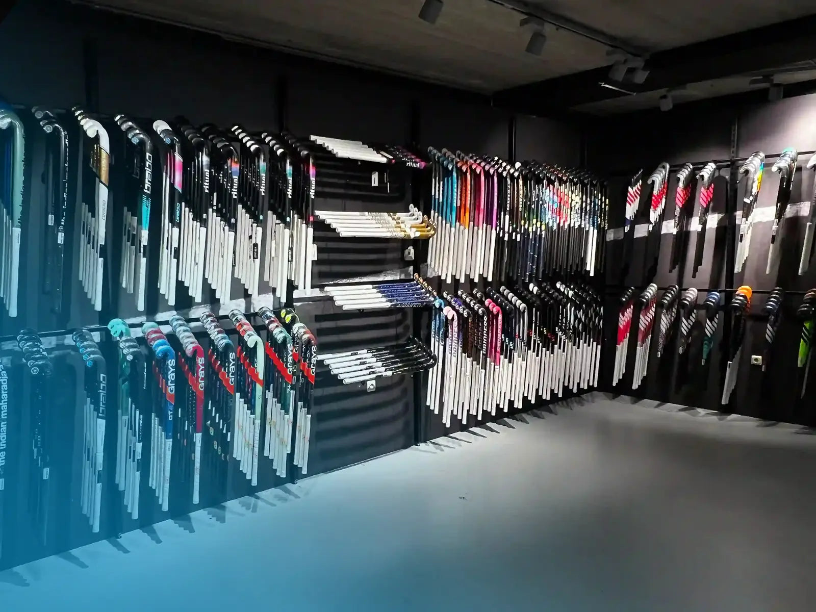 Alle sticks die te koop zijn bij de hockeywinkel aan de muur